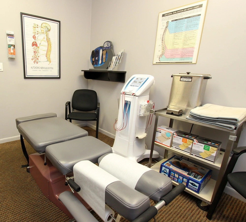 Chiropractic treatment room with adjustment table and medical equipment Chiropractic adjustment table in treatment room