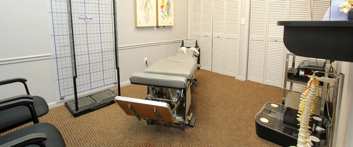 Medical examination room with adjustable patient table and spine model Medical exam room with patient table and spine model