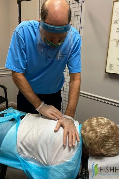 Chiropractor adjusting patient's back in treatment room Chiropractor adjusting patient's back on table